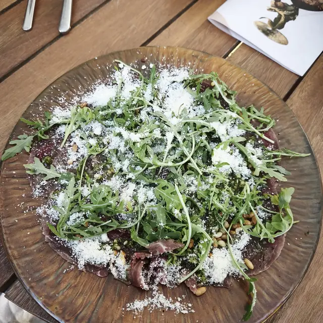 Carpaccio wołowe z rukolą i parmezanem na drewnianym talerzu
