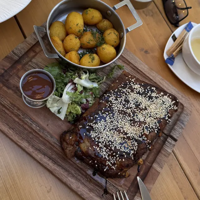 Żeberka BBQ na desce z pieczonymi ziemniakami